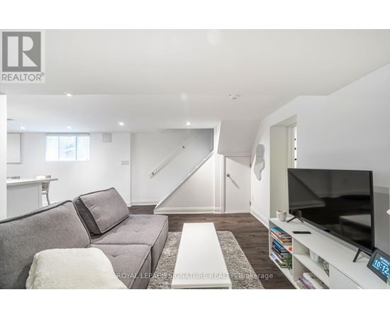 A living room with a grey couch and a television on a white stand.