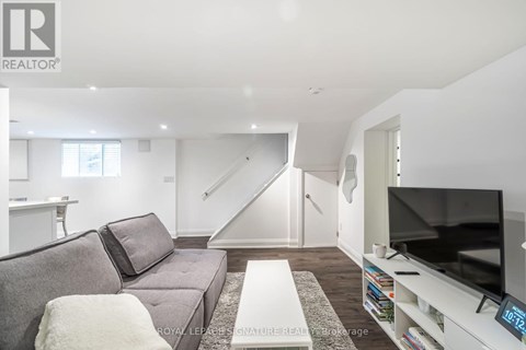A living room with a grey couch and a television on a white stand.