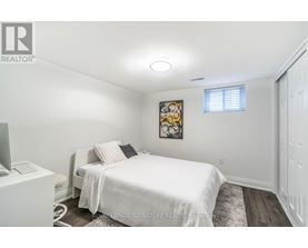 A bedroom with a white bed and a painting on the wall.