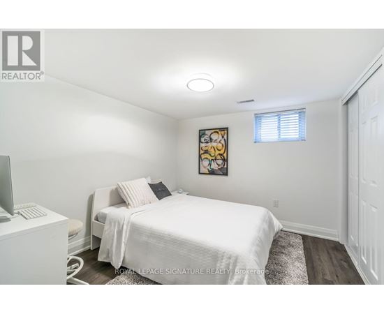 A bedroom with a white bed and a painting on the wall.