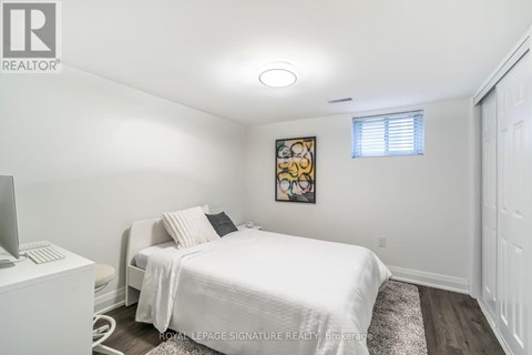 A bedroom with a white bed and a painting on the wall.