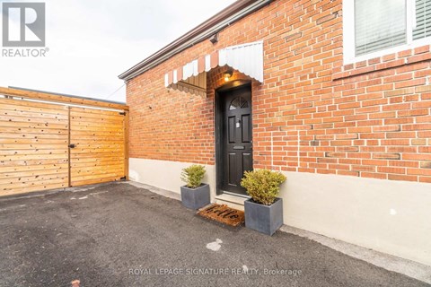 A red brick house with a black door and a wooden fence.