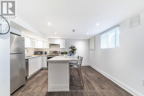 A kitchen with a refrigerator, sink, and a dining table with chairs.