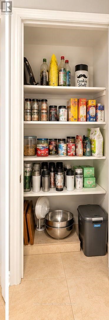 A kitchen pantry with a variety of food items and a trash can.