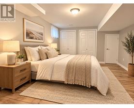 A bedroom with a large bed, a nightstand with a lamp, and a framed picture on the wall.