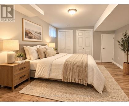 A bedroom with a large bed, a nightstand with a lamp, and a framed picture on the wall.