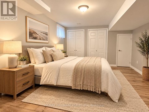 A bedroom with a large bed, a nightstand with a lamp, and a framed picture on the wall.