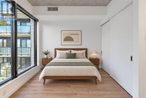 A bedroom with a large bed and a window overlooking a cityscape.