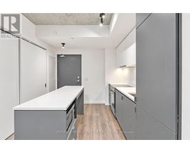 A kitchen with white countertops and grey cabinets.