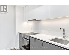 A white kitchen with a sink and a stove top oven.
