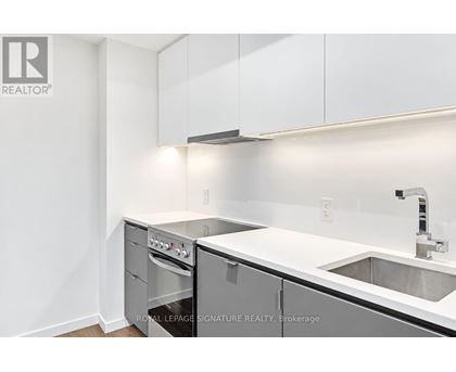 A white kitchen with a sink and a stove top oven.