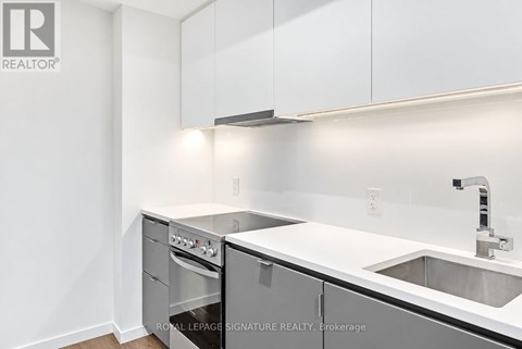 A white kitchen with a sink and a stove top oven.