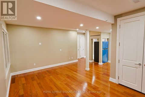 A room with wooden floors and white walls, with a door on the right side.