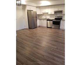 A kitchen with white cabinets and a wood floor.