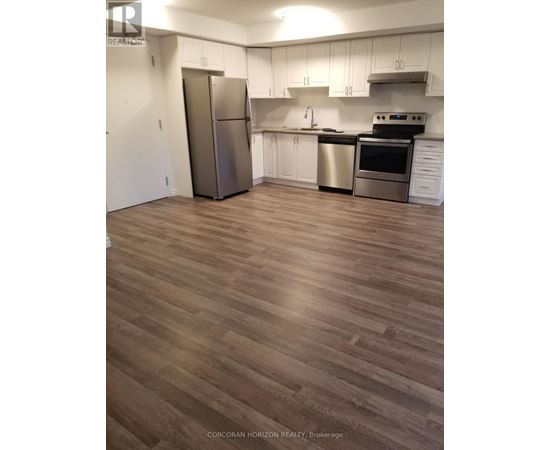 A kitchen with white cabinets and a wood floor.