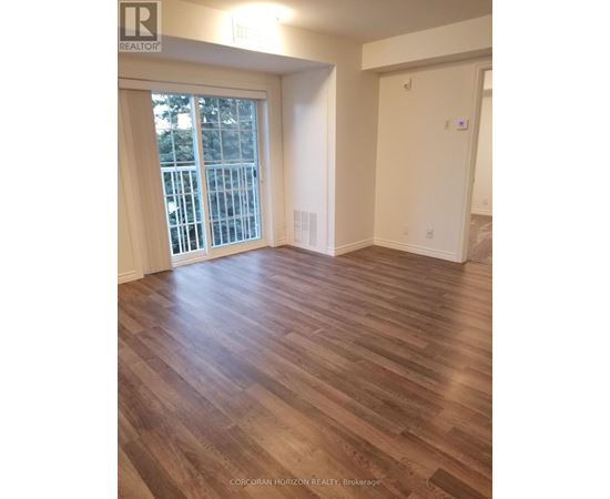 A room with wooden flooring and a sliding glass door leading to a balcony.