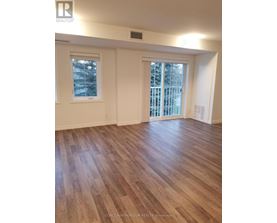 A room with wooden flooring and two windows.