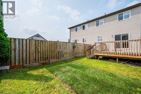 A wooden fence surrounds a green lawn in front of a two-story apartment building.