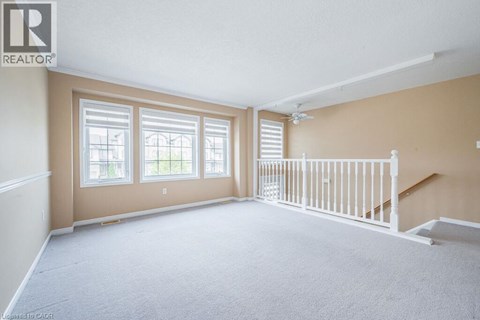 A spacious room with a carpeted floor and a staircase leading to another room.