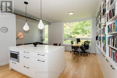 A white kitchen with a black chair and a clock on the wall.