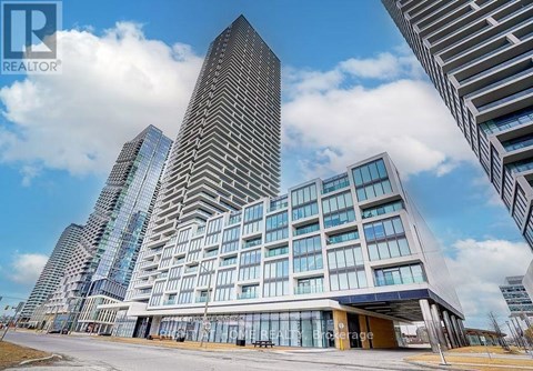 A modern building with a glass facade stands tall among other buildings.