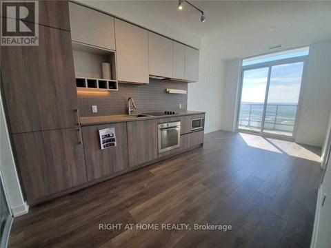 A kitchen with wooden cabinets and a large window overlooking the ocean.