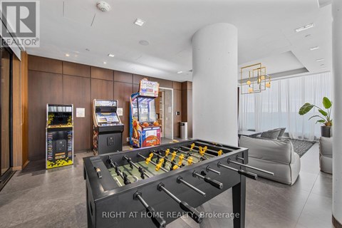 A foosball table is in the middle of a room with a couch and a plant.