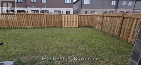 A backyard with a wooden fence and grass.