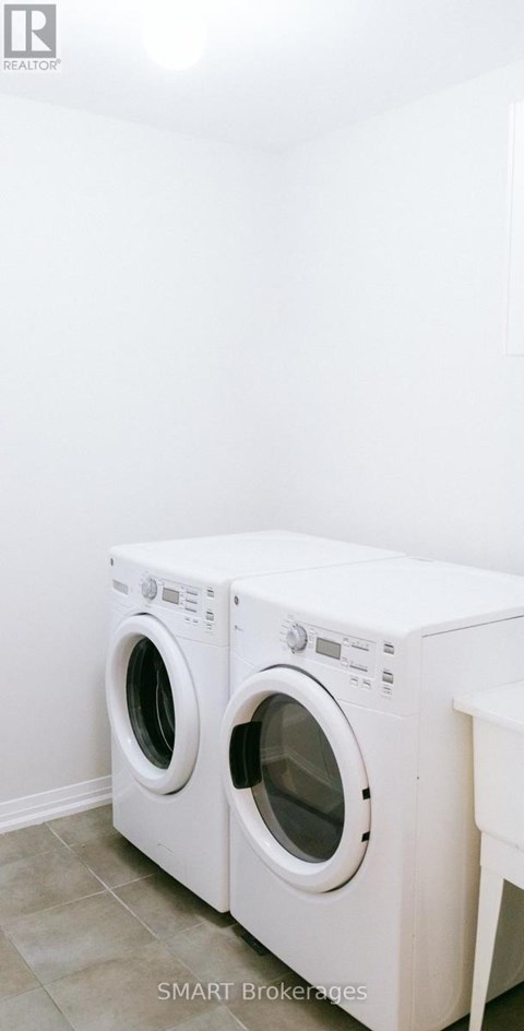 Two white washing machines in a laundry room.