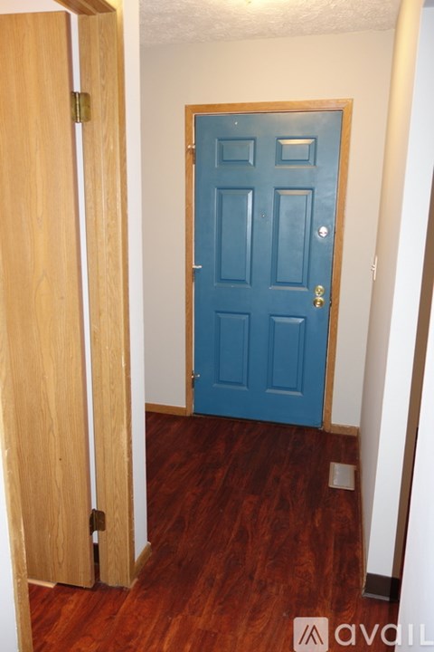 A blue door is in a white hallway.