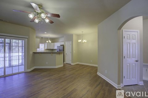 A spacious room with wood flooring and a ceiling fan.