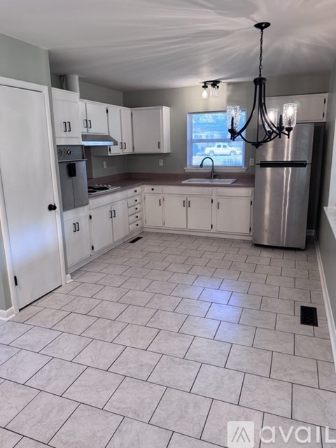 A kitchen with white cabinets and a tile floor.