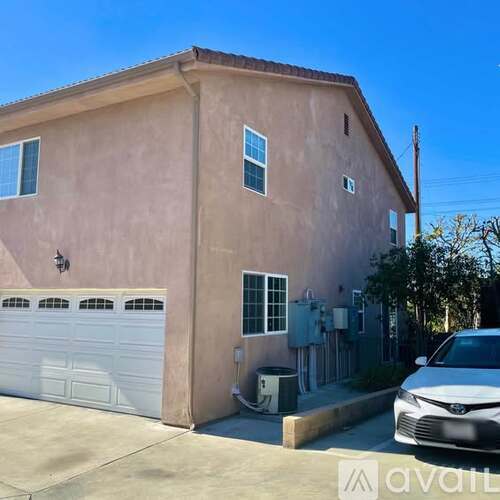 A beige house with a white garage door and a Toyota car parked in front.