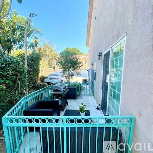 A patio with a turquoise railing and furniture.