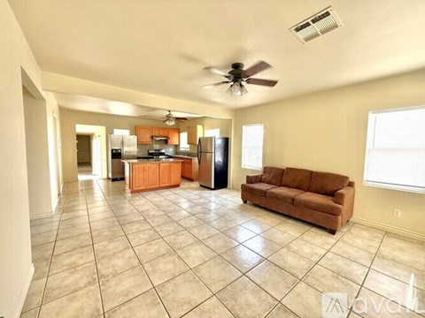 A spacious living room with a kitchen in the background.