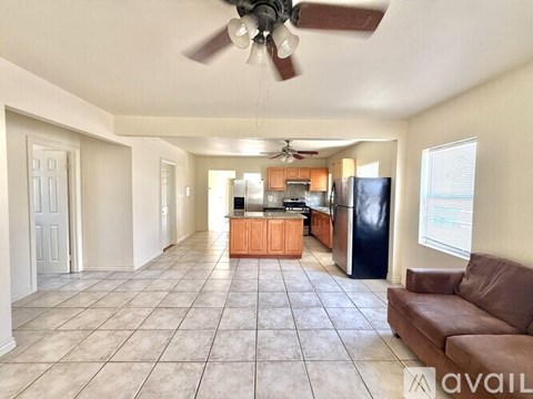 A spacious kitchen and living room with a tile floor and a ceiling fan.