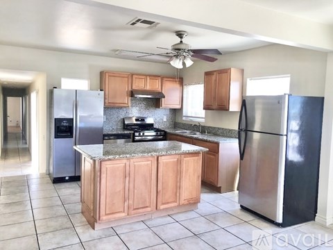 A kitchen with a refrigerator on the right and a stove top oven on the left.