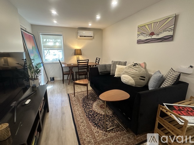 A living room with a black couch, a wooden coffee table, and a painting on the wall.