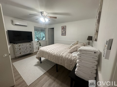 A bedroom with a neatly made bed and a television.