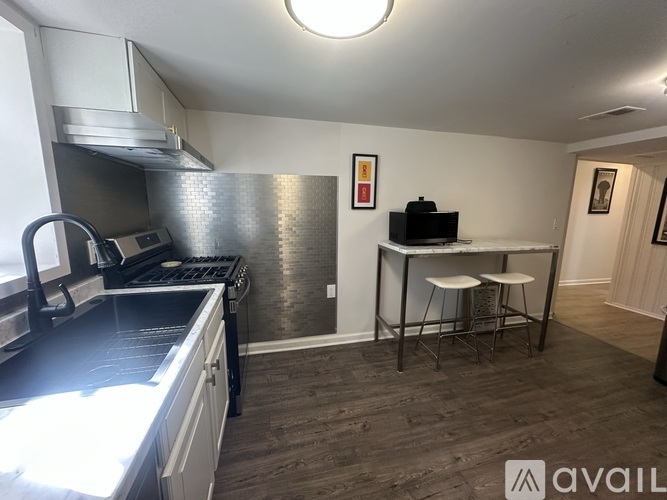 A kitchen with a black countertop and a stainless steel refrigerator.