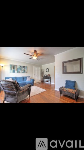 A living room with a sofa, two chairs and a fan.