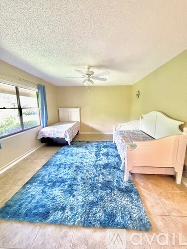 A bedroom with two beds and a blue rug.