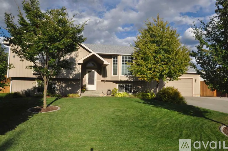 A house with a well-manicured lawn and trees in front.