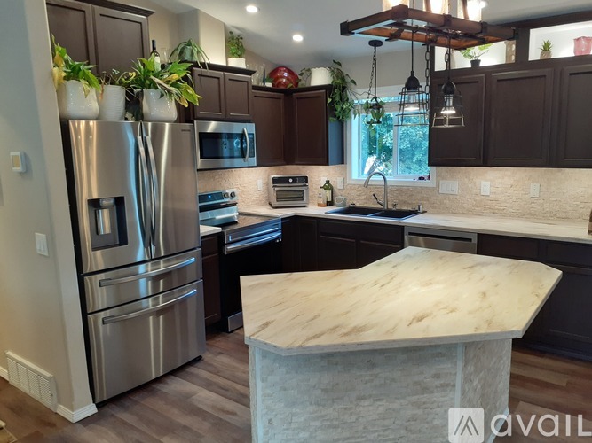 A kitchen with a marble island and stainless steel appliances.