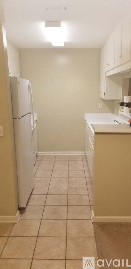 A kitchen with a white refrigerator and beige walls.