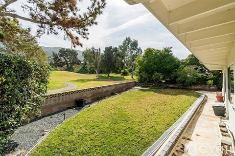 A backyard with a lawn and a retaining wall.