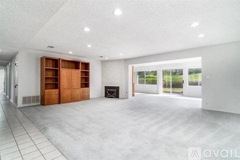 A spacious living room with a fireplace and a large window.