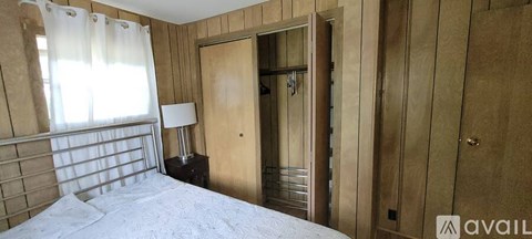 A bedroom with a bed, nightstand, and a window with curtains.