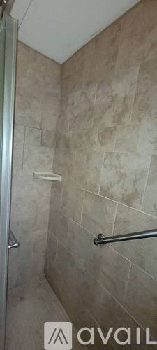A bathroom with beige tiled walls and a glass shower door.