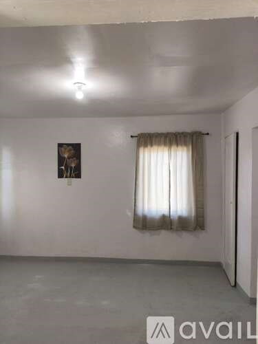 A room with a picture on the wall and a curtain on the window.